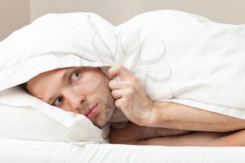 Portrait of funny scared Young Caucasian man in bed