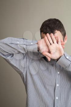 Young Caucasian man hiding his face with hands