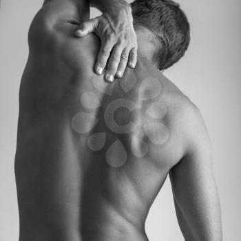 Back of Strong young Caucasian man with hand, black and white studio photo
