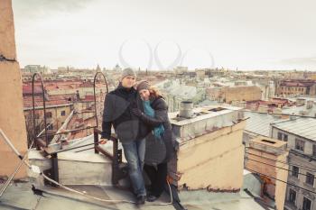 Outdoor portrait of young smiling Caucasian couple on the rooftop in St.Petersburg, Russia. Photo with toning effect