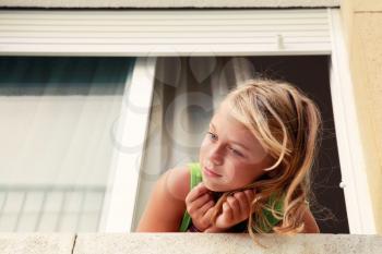 Little blond Caucasian girl in the window, outdoor portrait, retro toned filter effect
