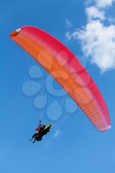 Red paraglider in the blue sky with clouds