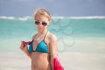 Outdoor portrait of beautiful Caucasian teen girl in blue swimsuit and red shawl on the ocean coast