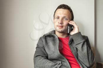 Portrait of sitting young adult man talking on mobile phone