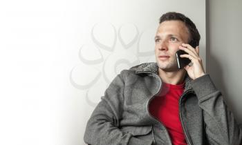 Portrait of sitting young adult Caucasian man talking on mobile phone