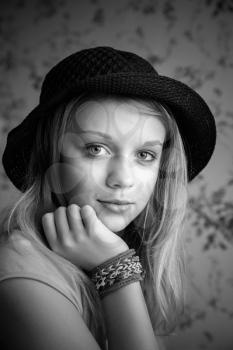 Monochrome portrait of beautiful blond teenage girl in black hat and rubber loom bracelets