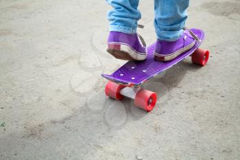 Riding skateboarder feet fragment in jeans and gumshoes