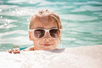 Beautiful little blond girl with sunglasses in outdoor pool, closeup summer portrait, toned photo, old style filter effect