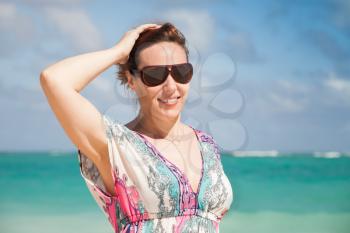 Young happy Caucasian woman in sunglasses. Summer outdoor portrait on the ocean coast
