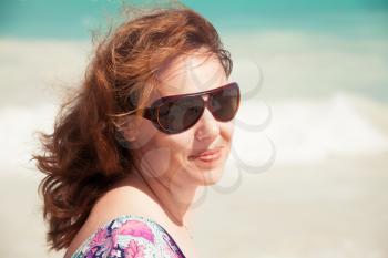 Young smiling Caucasian woman in sunglasses. Summer outdoor portrait on the sea coast