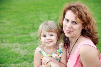 Outdoor summer portrait of a real Caucasian family, young mother with her small cute daughter