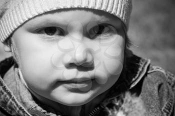 Closeup monochrome portrait of small Caucasian girl on the walk, outdoor photo