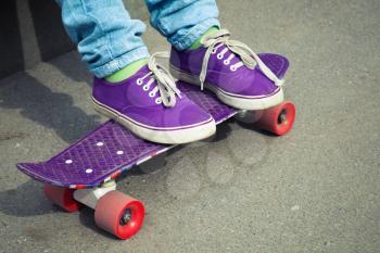 Teenager feet in blue jeans and gumshoes with skateboard