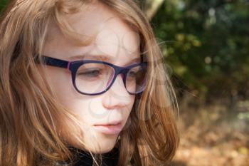 Beautiful blond Caucasian teenage girl in glasses, outdoor closeup portrait
