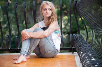 Beautiful blond Caucasian teenage girl on balcony, outdoor summer portrait