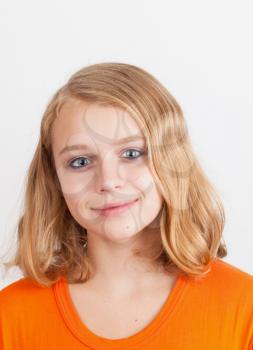 Smiling blond Caucasian teenage girl, closeup studio portrait on light gray background