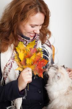 Portrait of Young Caucasian woman in traditional Russian neck scarf with white cat and colorful autumn maple leaves