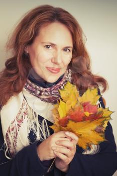 Portrait of beautiful Young Caucasian woman in traditional Russian neck scarf with colorful autumn maple leaves. Vintage tonal correction filter, retro style photo filter