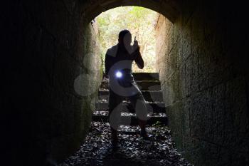 Young man with radio set and flashlight enters the stone tunnel