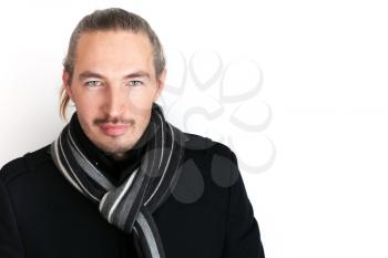 Closeup studio portrait of serious young Asian man in black coat and woolen scarf over white wall background