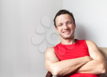 Positive young smiling Caucasian man sitting with crossed arms