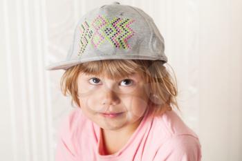 Closeup portrait of cute confused Caucasian blond baby girl in gray cap