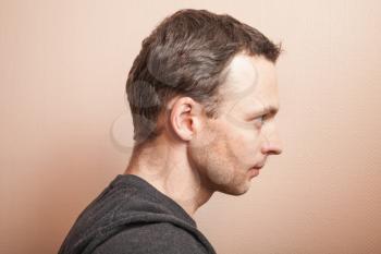 Young serious Caucasian man profile studio portrait over gray wall background