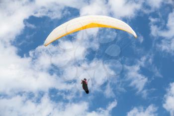 Amateur paraglider in blue sky with clouds