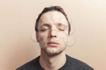 Young Caucasian man with closed eyes. Studio portrait over gray wall background, old style photo filter tonal correction effect