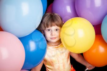 Studio portrait of little Caucasian blond girl with colorful balloons