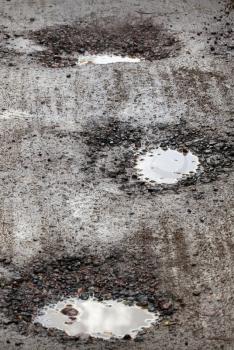 Damaged wet road with holes