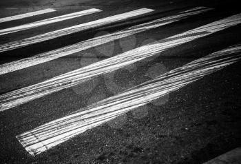 Danger pedestrian crossing with white rectangles and braking tracks on the dark asphalt road