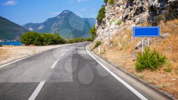 Mountain asphalt road and empty blue road sign in Montenegro
