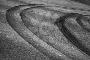 Abstract road background with curved tires tracks on dark asphalt. Dangerous turn