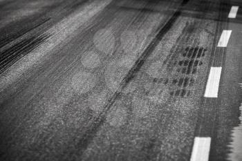 Asphalt road with marking lines and tire tracks. Close up photo with selective focus