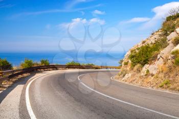 Turn of mountain highway with blue sky and sea on a background