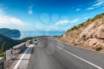 Turning mountain highway with blue sky and sea on a background