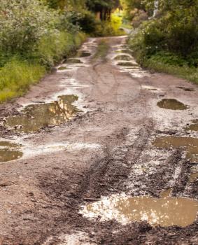Rural damaged road with muds and holes
