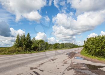 Rural asphalt road and clouds on blue sky in summer day