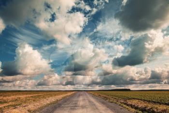 Empty country road with dramatic cloudy sky. Vintage toned effect