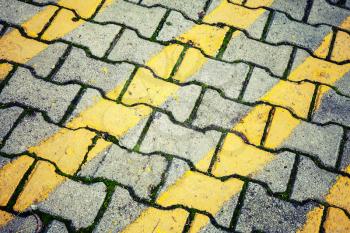 Abstract urban background texture. Yellow lines pattern over gray cobblestone road pavement. Vintage photo filter