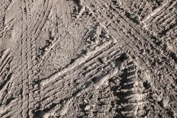 Background texture of dark brown road dirt with tire tracks 