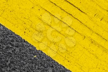 Abstract yellow road marking fragment with tire track relief on gray asphalt