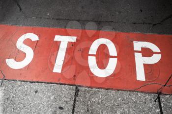 Road marking with stop label over red line on urban pavement