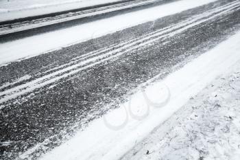 Winter slippery road background, asphalt pavement under fresh snow layer