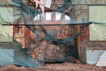 Old living house is under reconstruction, facade with arch is covered with green protection mesh