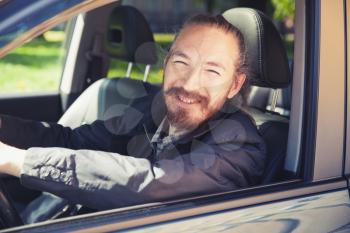Smiling Asian man as a driver of modern Japanese suv, outdoor portrait in open car window, vintage stylized photo with tonal correction photo filter
