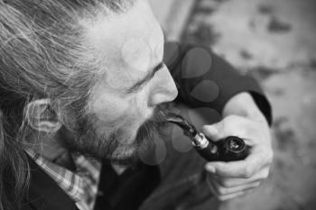 Man smoking pipe, black and white photo with selective focus
