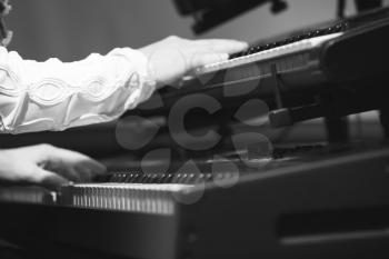 Pop music. Electric piano player plays on two keyboards in one time, black and white photo with selective focus