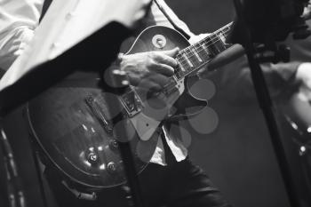 Rock and roll music background, guitar players on a stage, black and white, selective focus